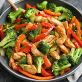 A vibrant stir-fry dish featuring chicken, broccoli, and mixed bell peppers garnished with sesame seeds.