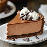 A slice of chocolate cake with white whipped cream on top.